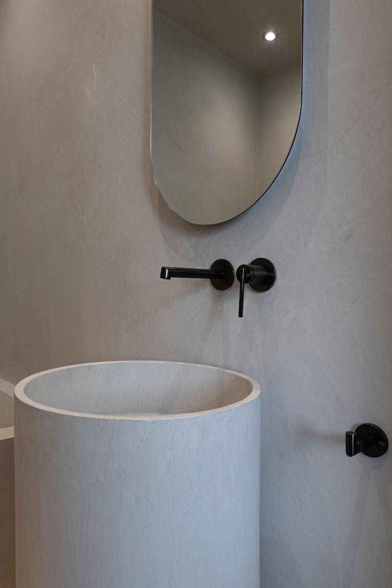 Pedestal basin with wall-mounted black tap